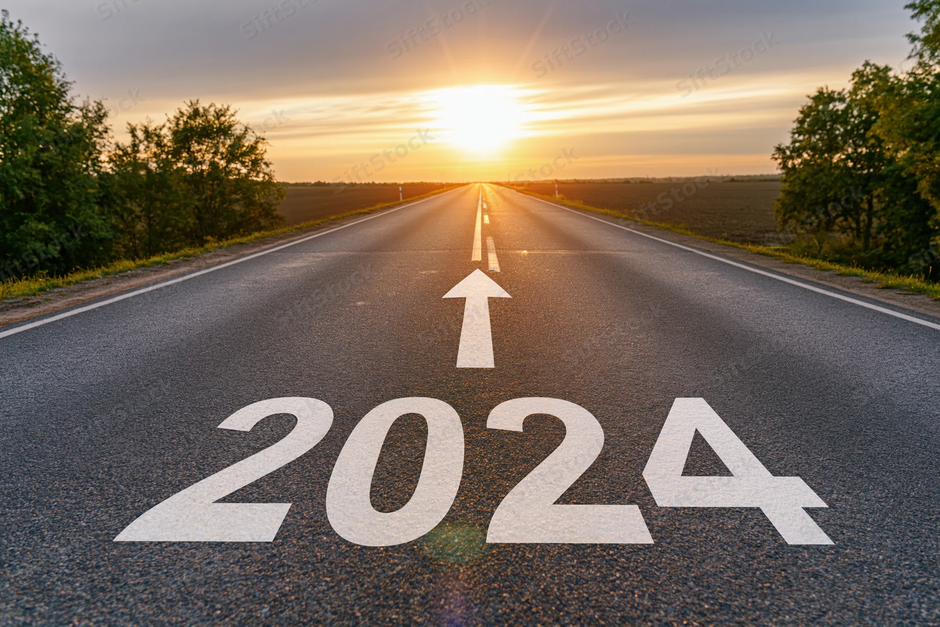 Asphalt road marked with 2024 and arrow pointing toward sunrise on horizon