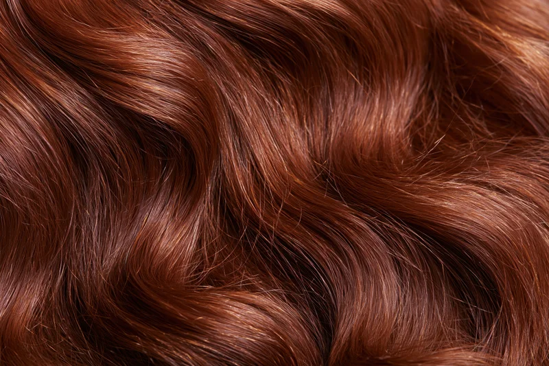Close-up of flowing auburn red hair with glossy texture