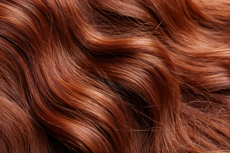 Closeup of flowing auburn red hair with wavy texture and glossy shine
