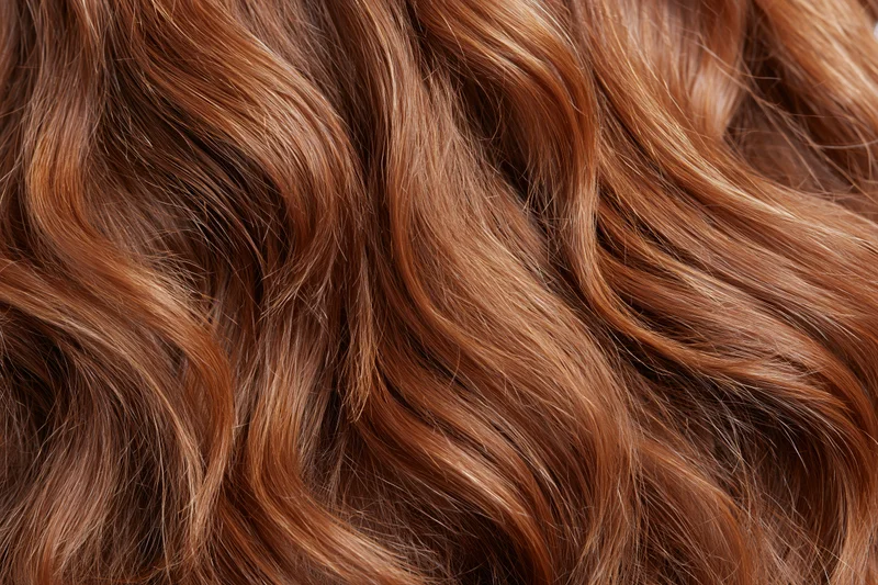 Close-up of wavy auburn hair with natural shine and volume