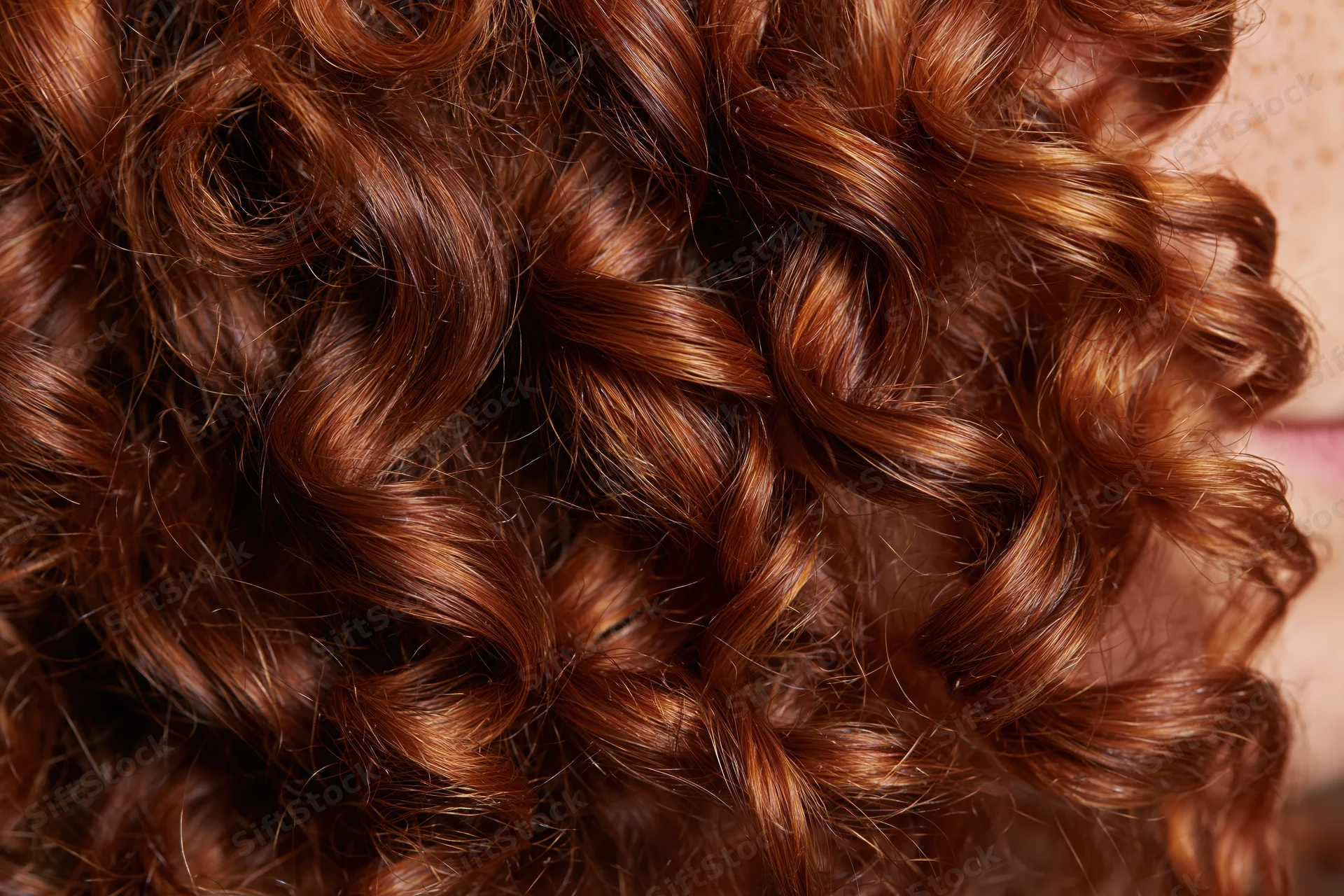 Extreme close-up of natural curly auburn hair showing texture and shine