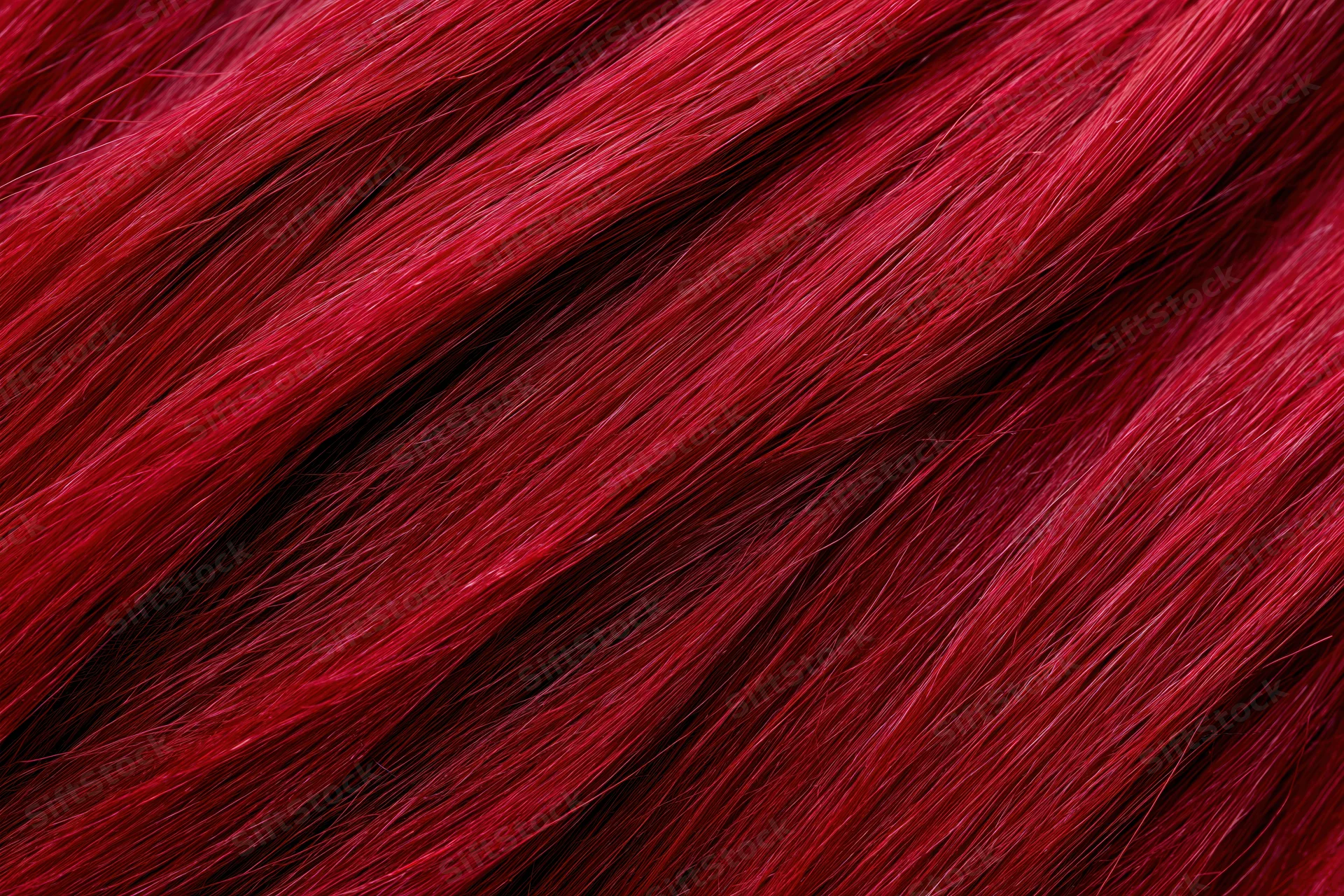 Close-up of vibrant red dyed human hair strands showing glossy texture