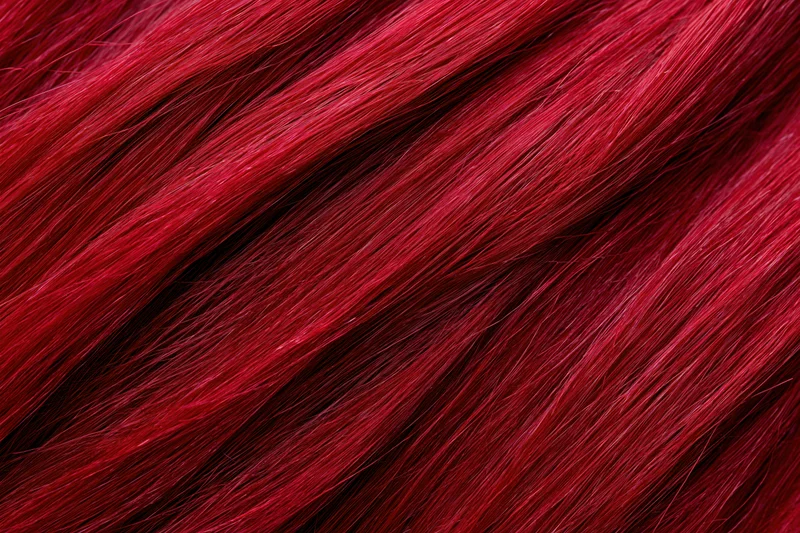Close-up of vibrant red dyed human hair strands showing glossy texture