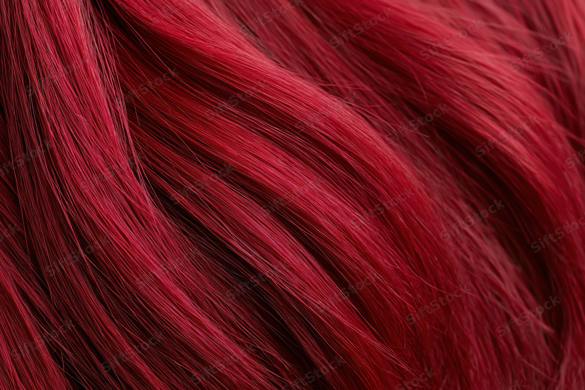 Extreme close-up of vibrant red dyed human hair strands showing glossy texture