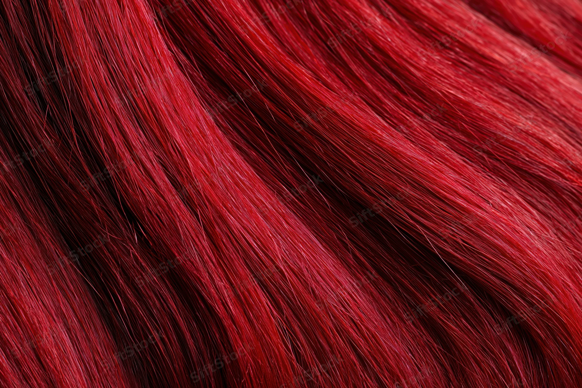 Close-up of vibrant red dyed human hair strands showing glossy texture
