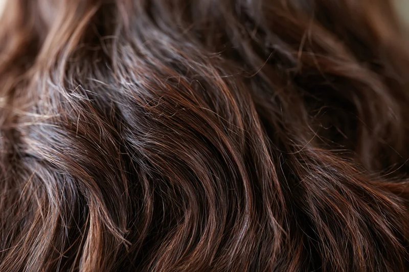 Extreme close-up of wavy brown human hair showing texture and natural highlights