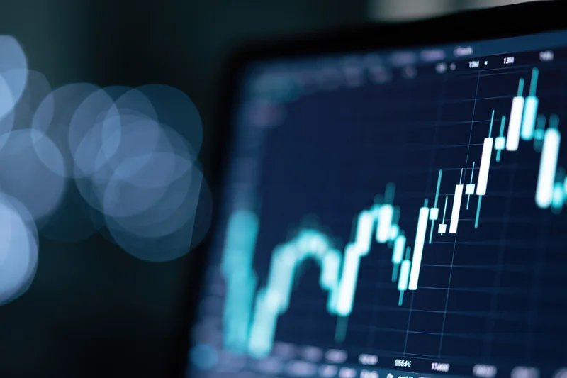 Financial candlestick chart showing upward trend on digital screen with blurred background