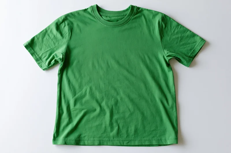 Plain green cotton t-shirt laid flat on white background