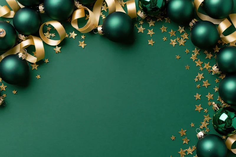 Dark green christmas ornaments and gold ribbon arranged in a frame on a green surface with copyspace
