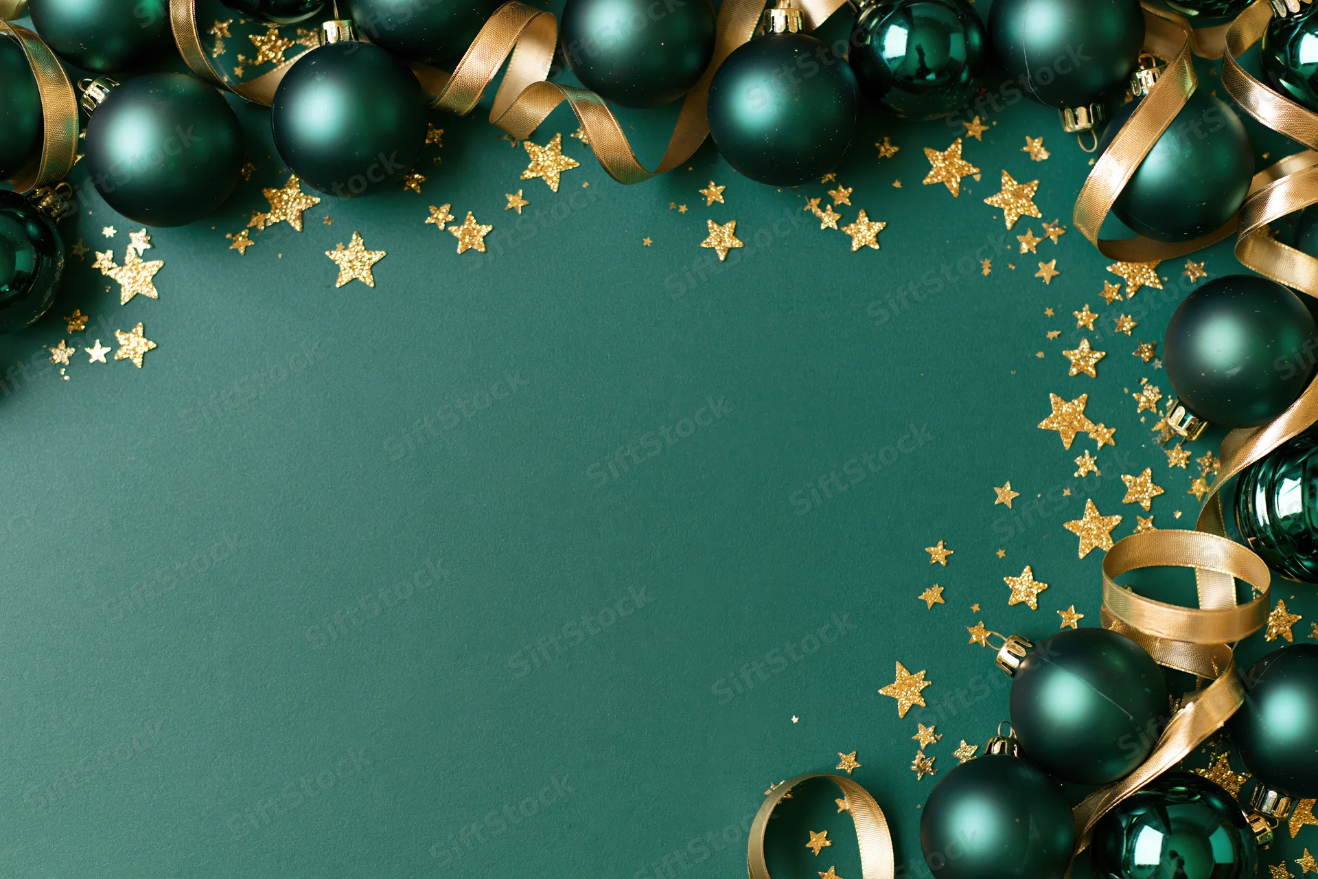 Dark green christmas ornaments and gold ribbon arranged in a frame on a matching green surface with scattered glitter stars and copyspace in the center
