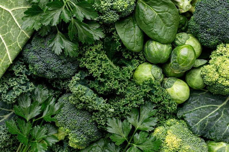 Dense flat lay of mixed green vegetables including broccoli kale brusselsprouts and spinach filling the frame