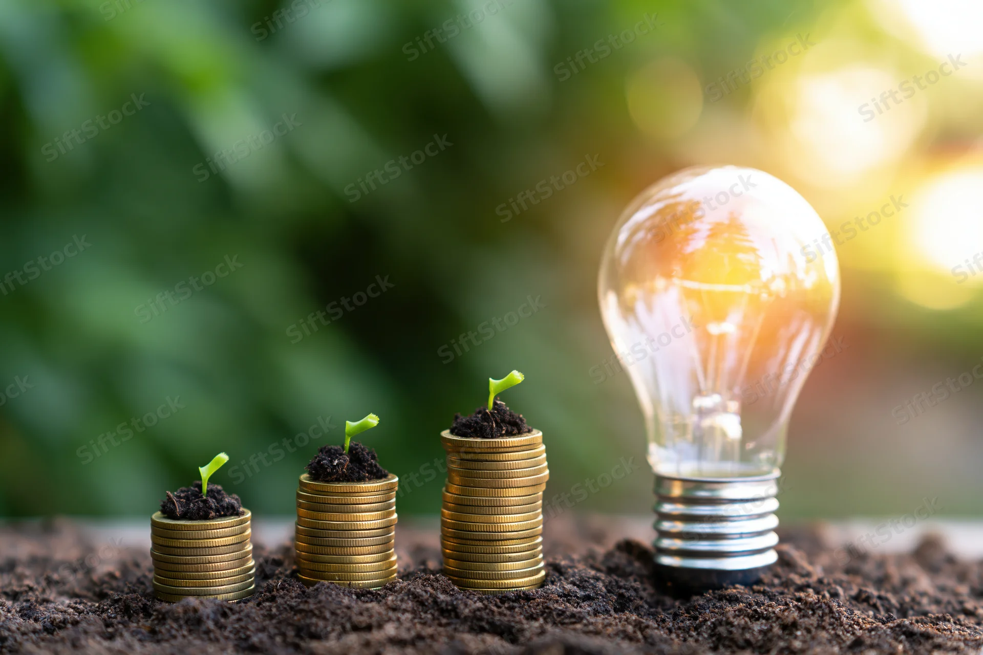 Stacks of gold coins with sprouting plants in soil beside a glowing lightbulb outdoors