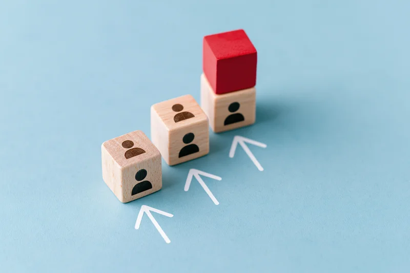 Wooden cubes arranged in ascending staircase with white arrows pointing upward on blue background