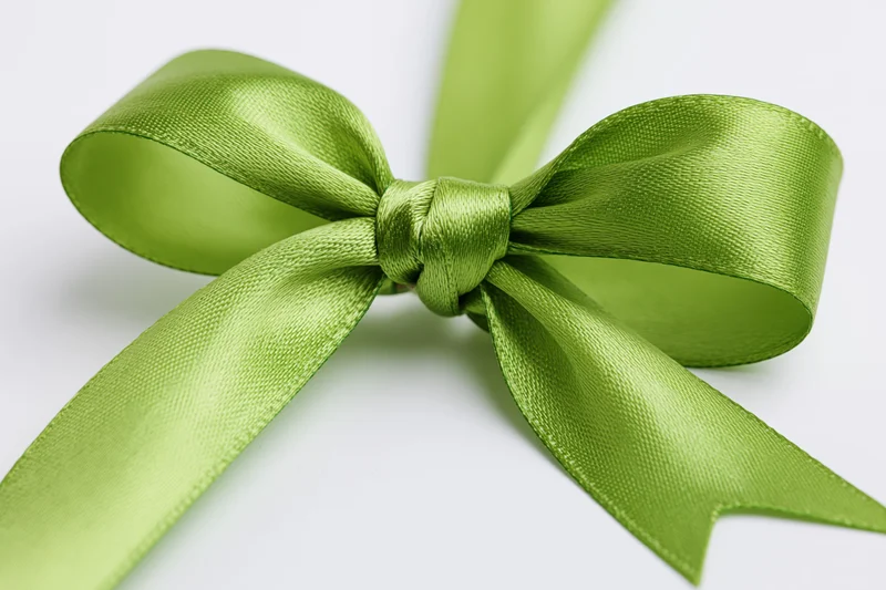 Green satin ribbon tied in a full decorative bow on white background