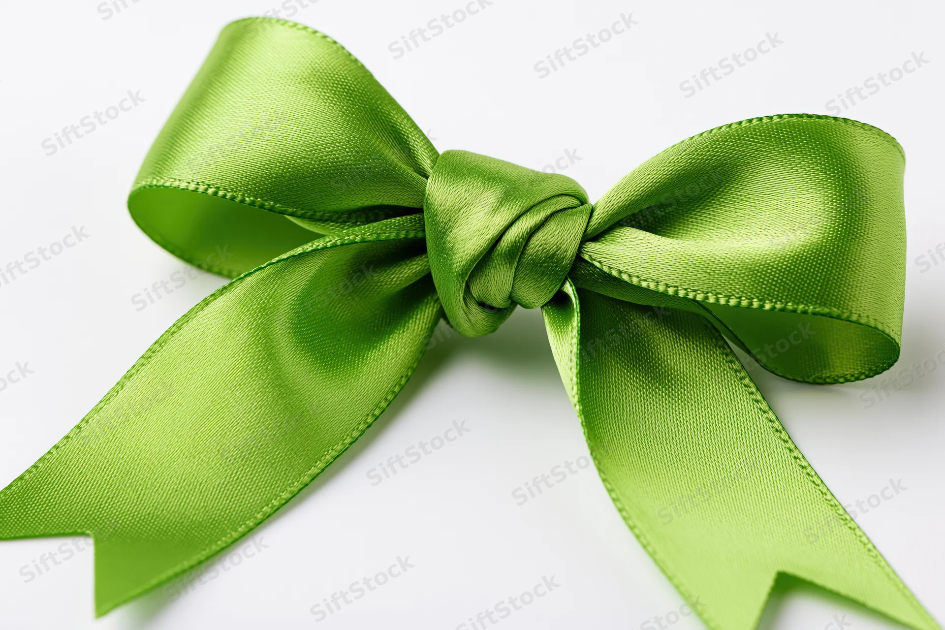 Green satin bow tied in full decorative knot on white background