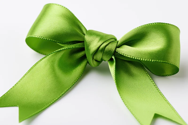 Green satin bow tied in full decorative knot on white background