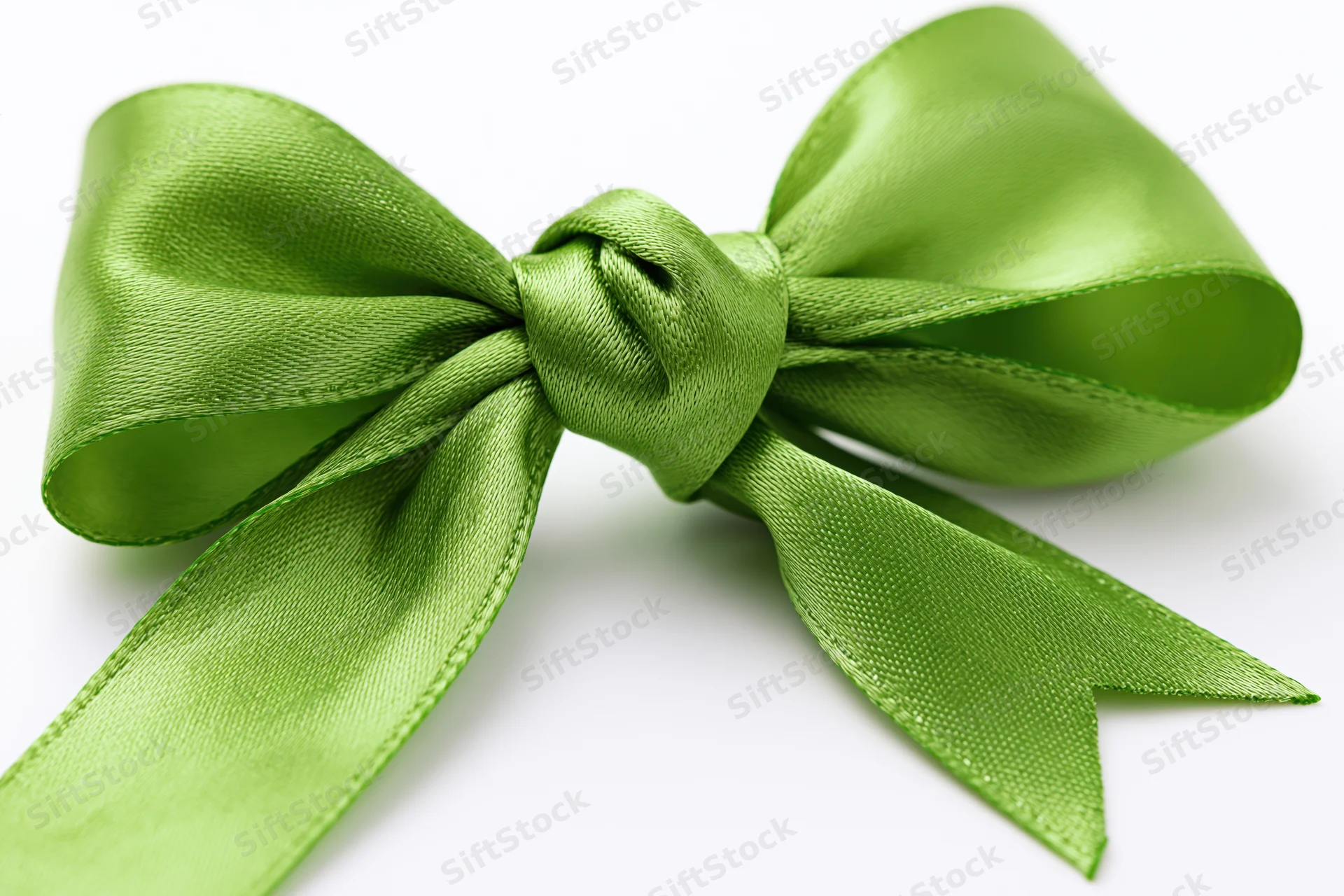 Green satin bow tied in a full decorative knot on white background