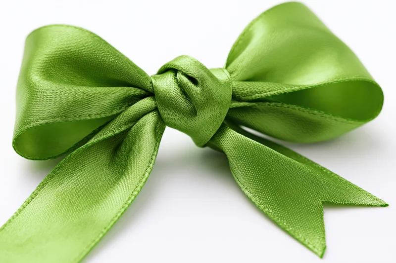 Green satin bow tied in a full decorative knot on white background