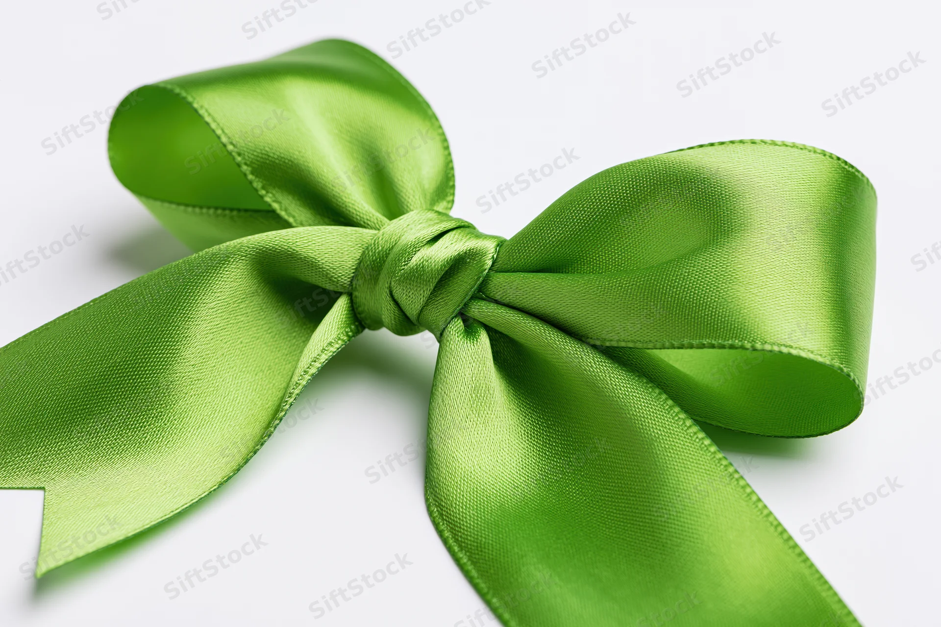 Green satin bow tied in a full decorative knot on white background