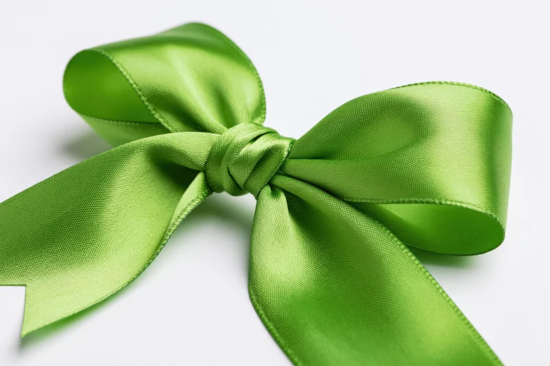 Green satin bow tied in a full decorative knot on white background