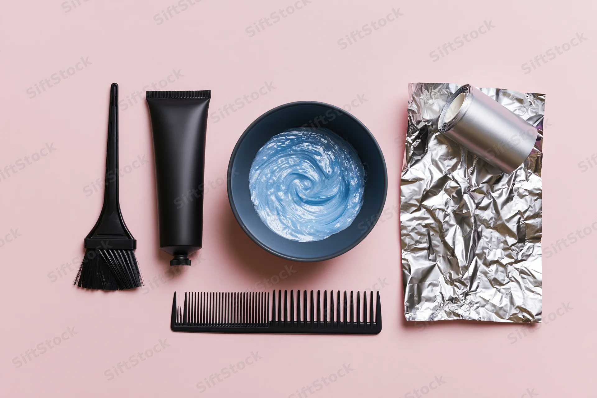 Hair coloring tools arranged in flat lay on pink surface