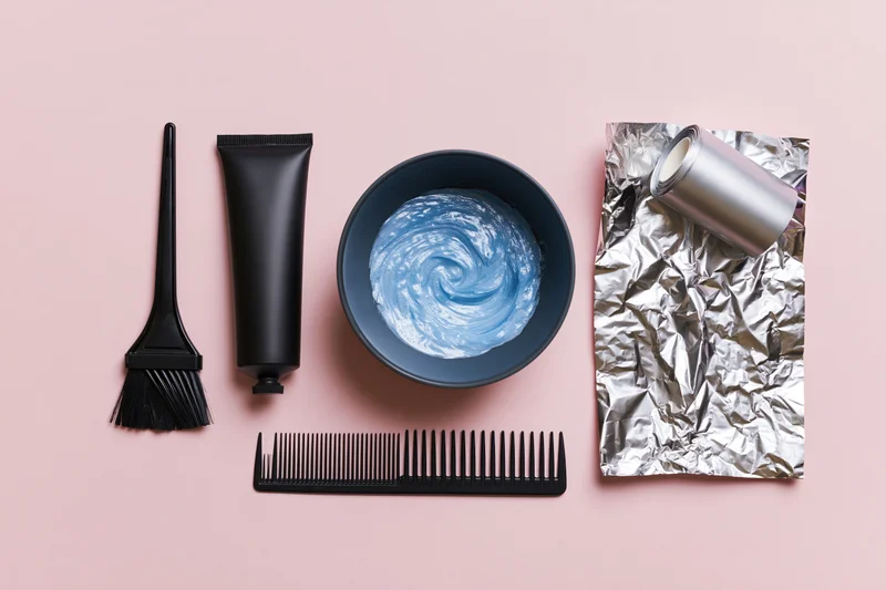 Hair coloring tools arranged in flat lay on pink surface
