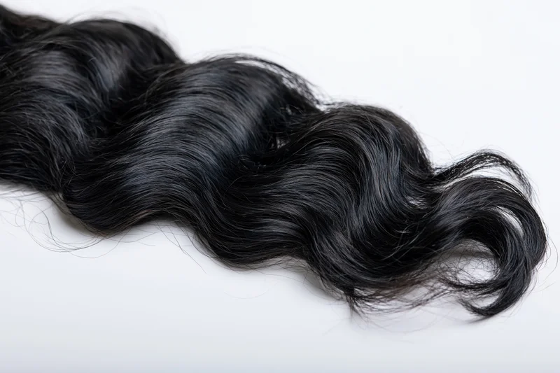 Long black wavy hair extension floating against white background