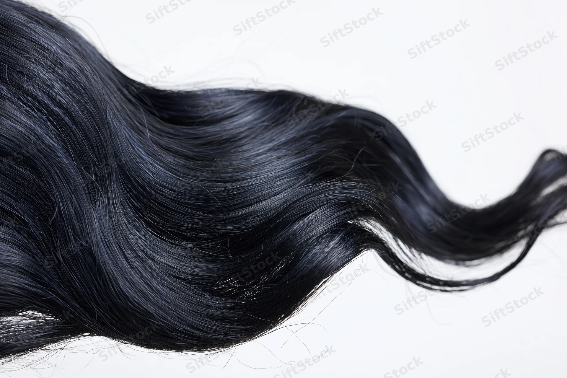 Long black wavy hair extension floating midair against white background