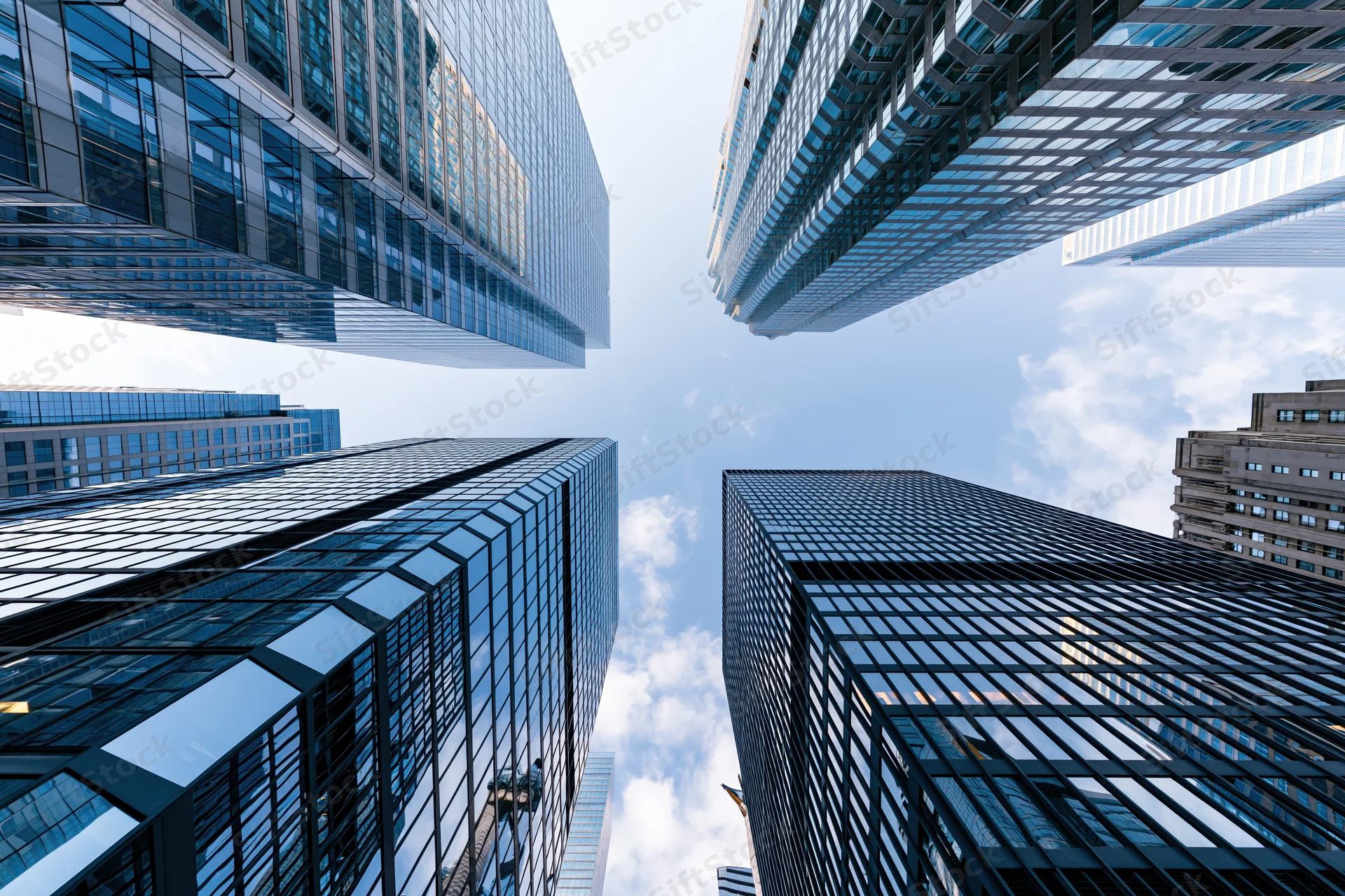 Low-angle view of glass skyscrapers rising into a blue sky in a modern city center