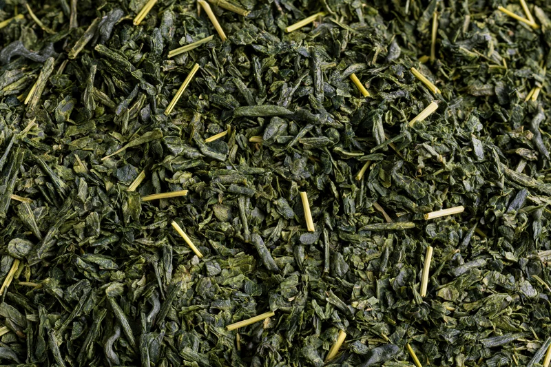Loose dried green tea leaves spread flat filling the entire frame