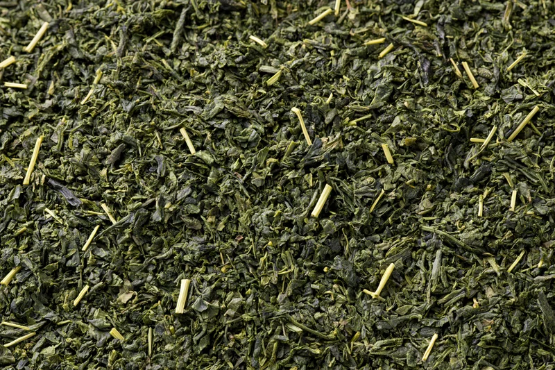 Loose dried green tea leaves spread flat filling the frame