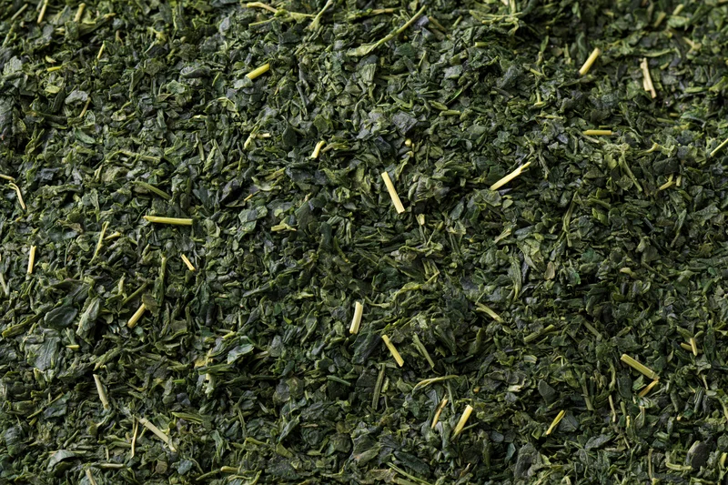 Dried green tea leaves spread flat filling the frame