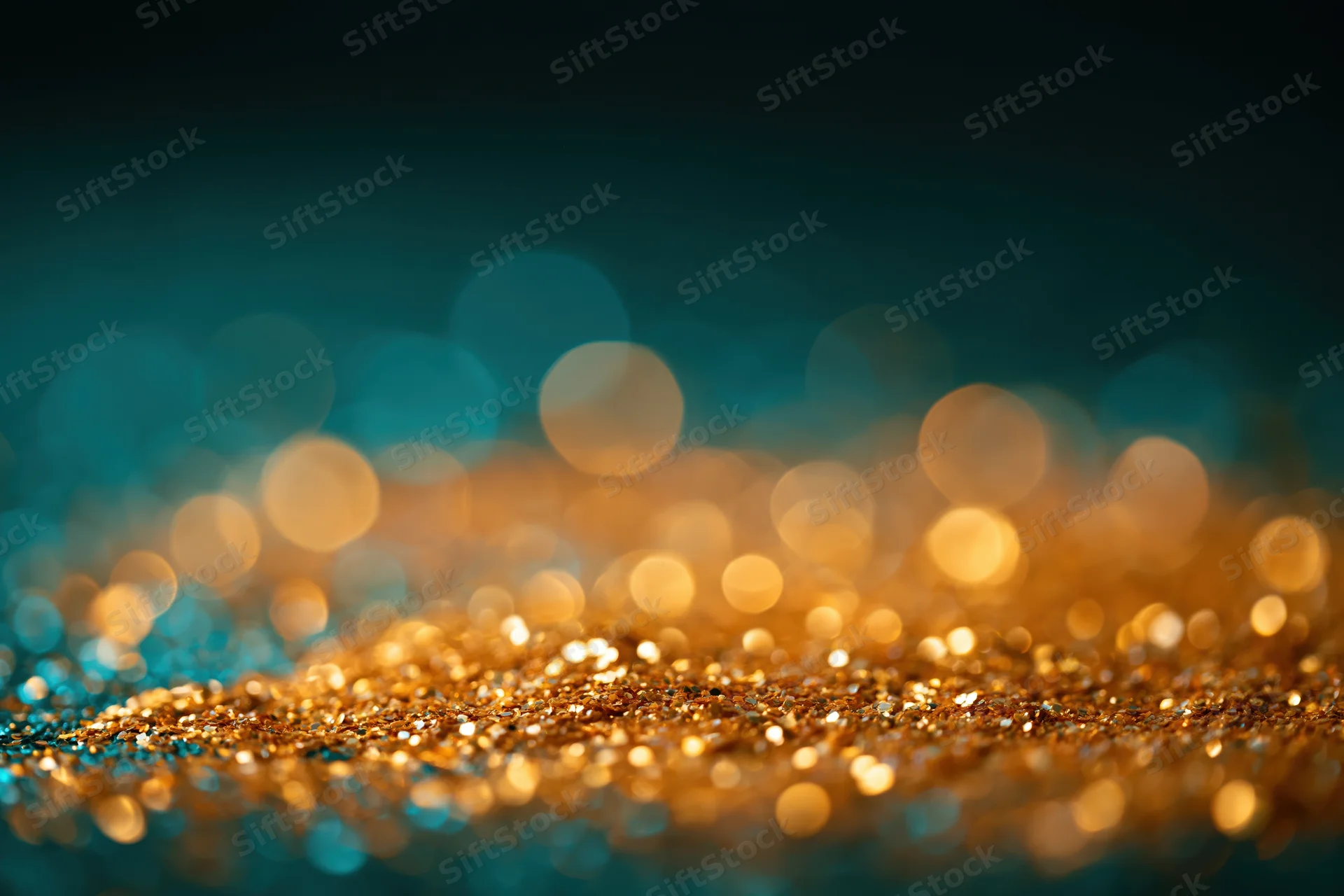 Scattered gold glitter on a dark surface with bokeh lights in the background