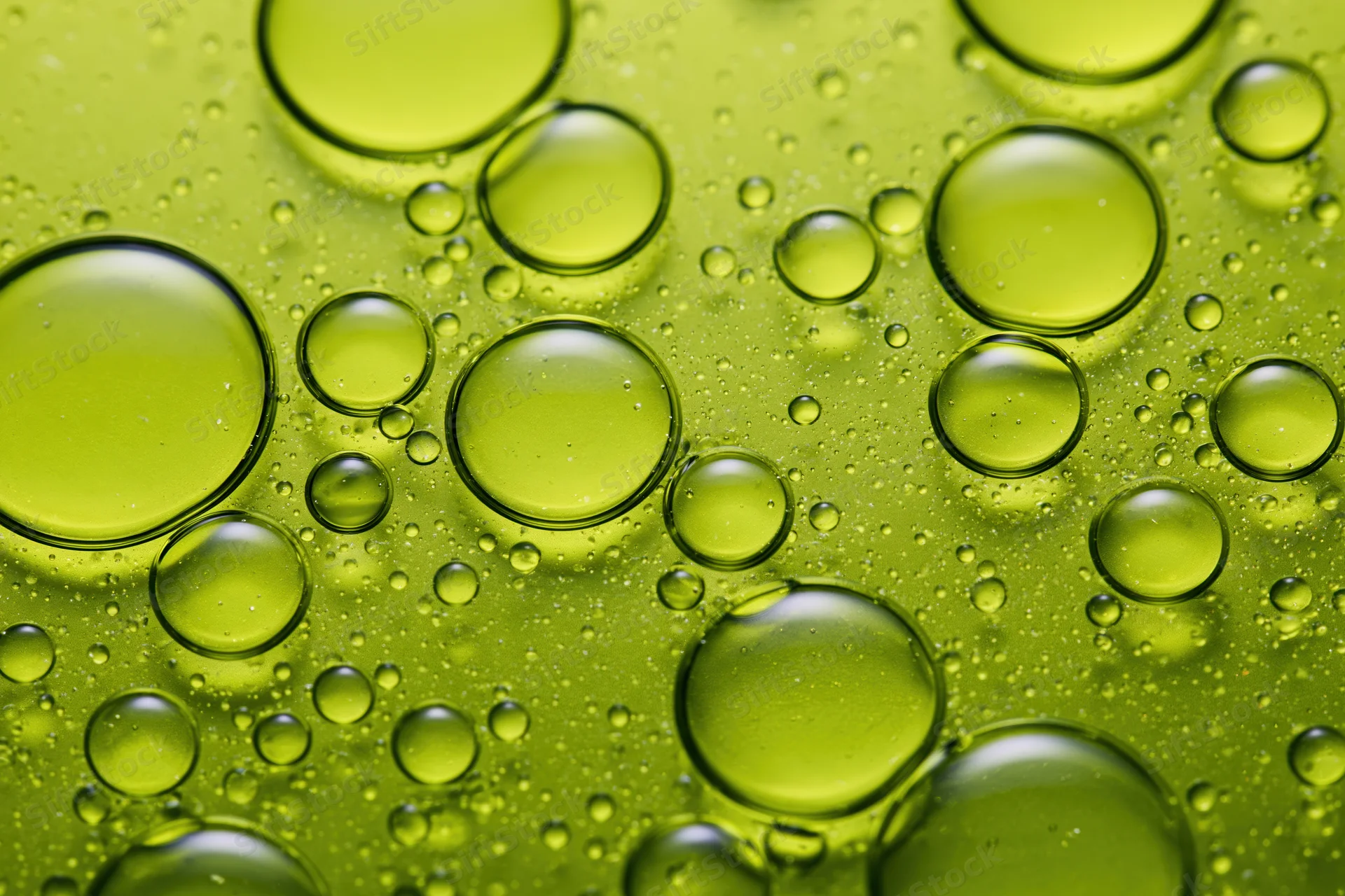 Macro closeup of scattered oil droplets on a green surface