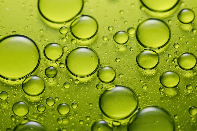 Macro closeup of scattered oil droplets on a green surface