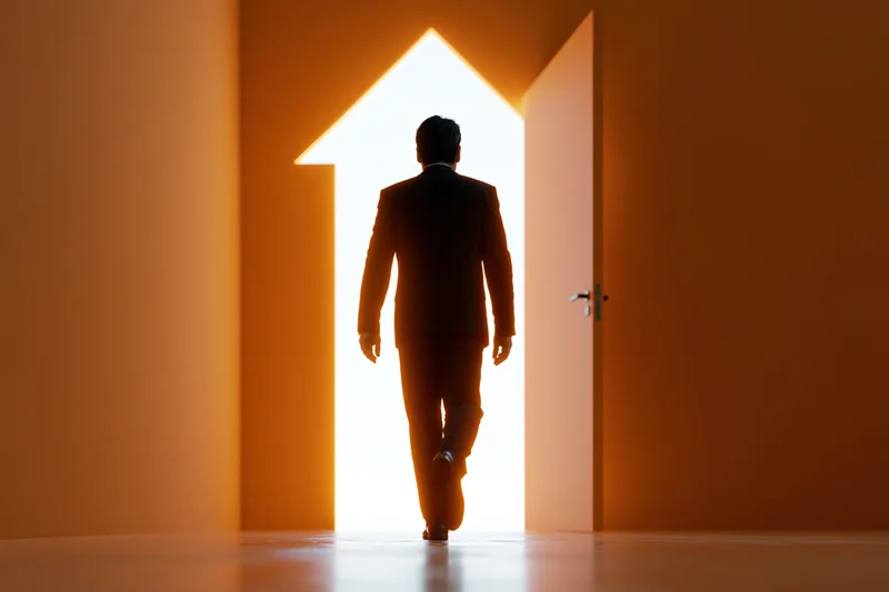 Businessman in suit walking toward glowing doorway shaped like an arrow