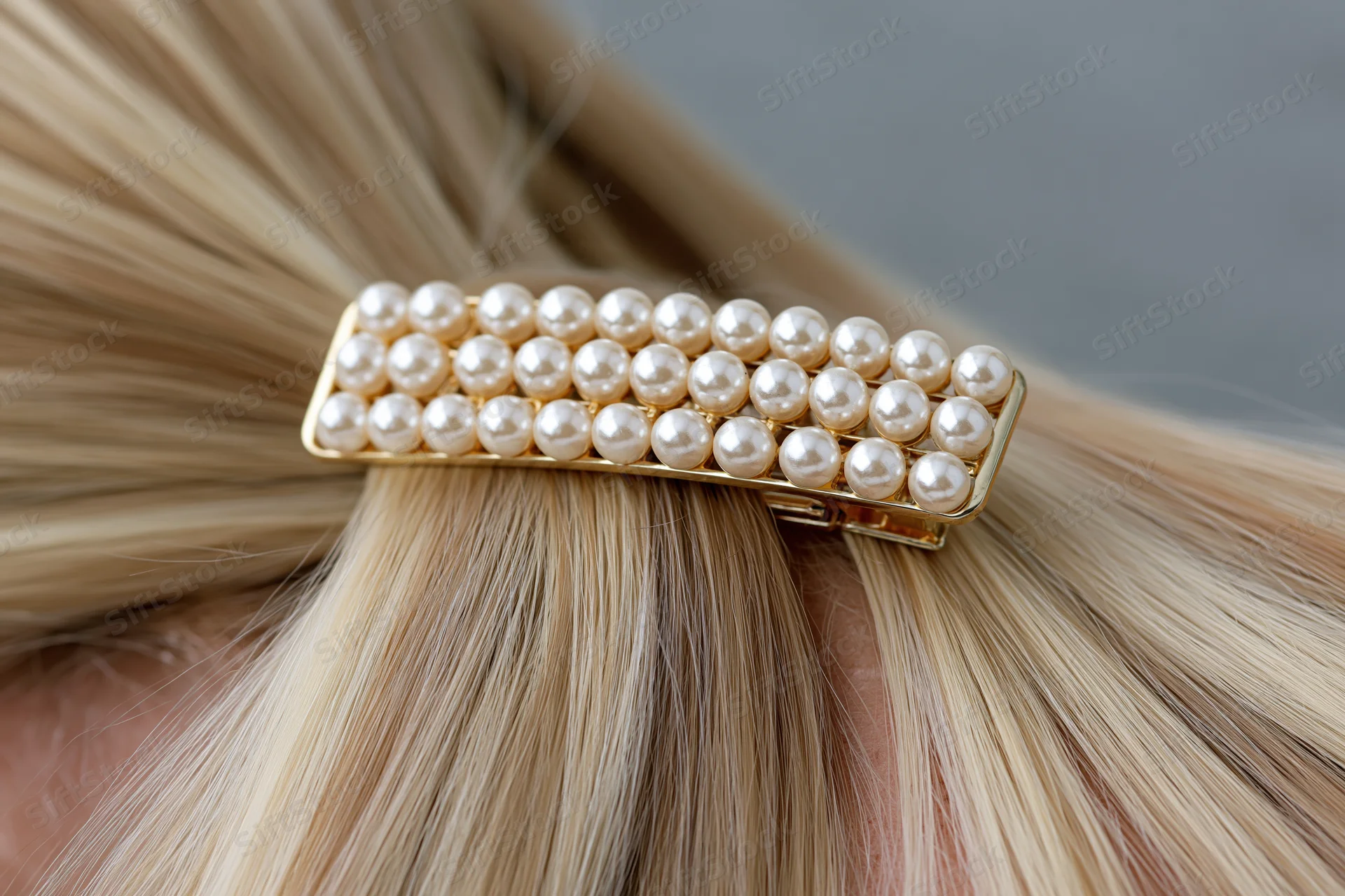 Pearl-studded gold claw hair clip securing a half-up section of blonde hair