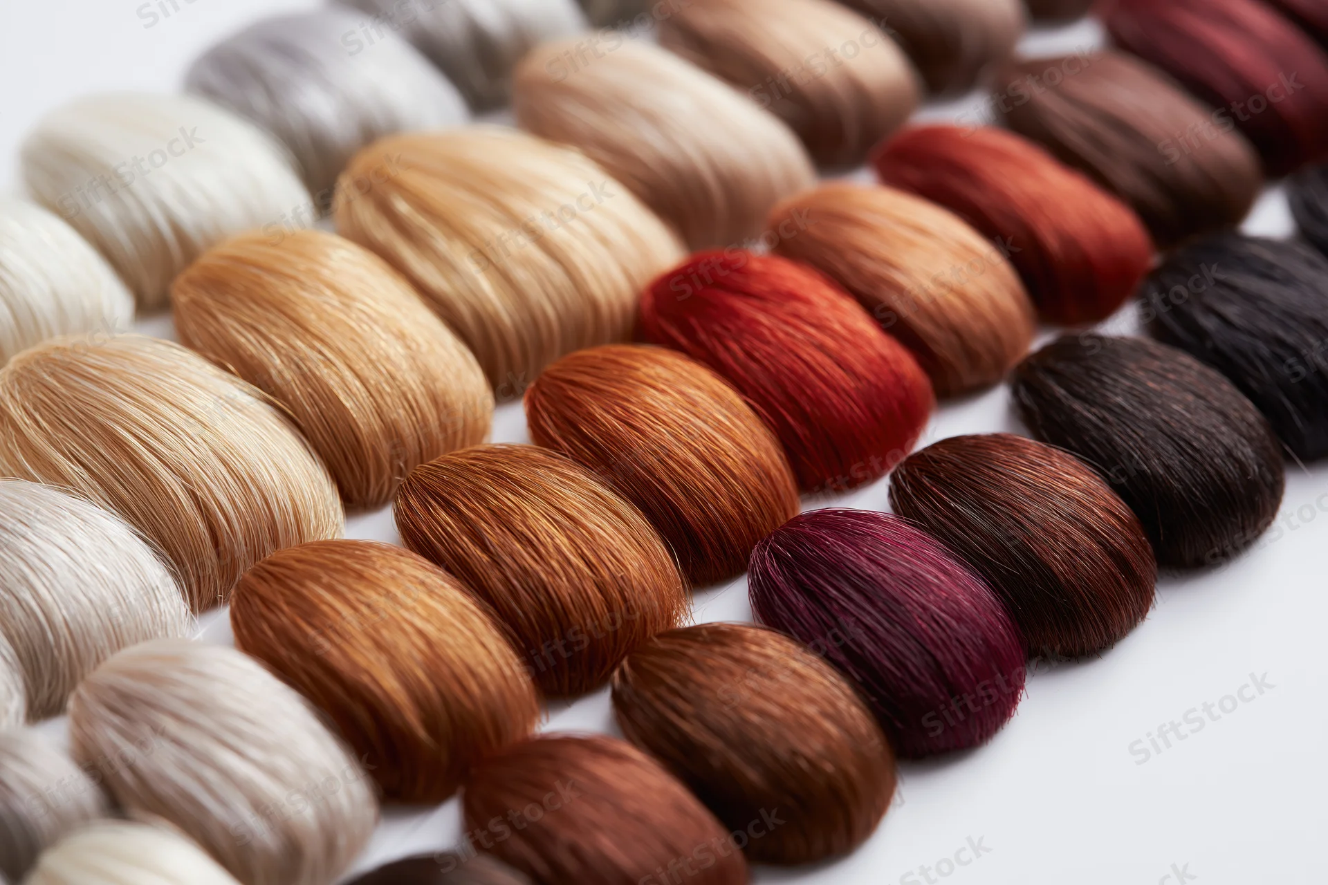 Rows of hair color swatches arranged in a gradient on a white surface