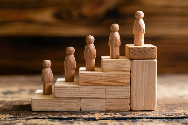 Wooden figurines arranged on ascending blocks representing career progression