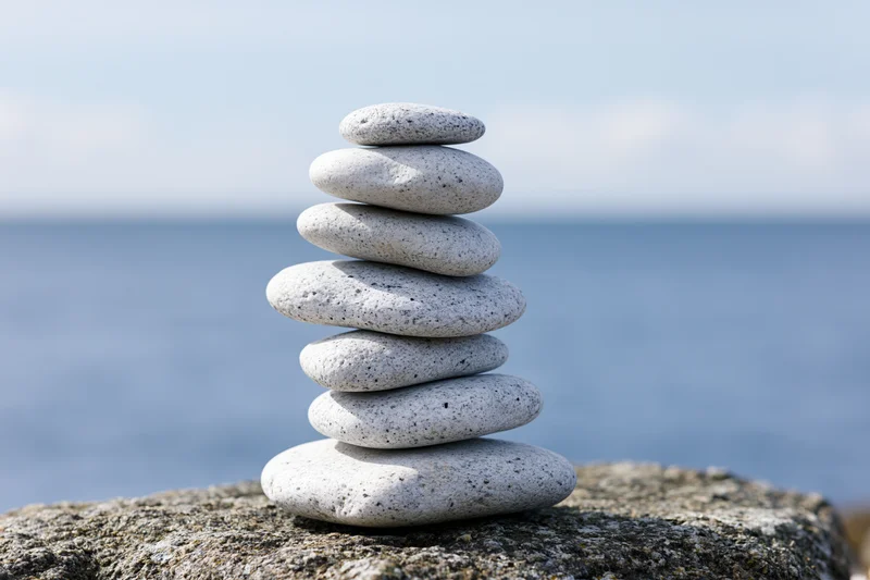 Balanced stack of smooth gray pebbles on a rocky outcrop by the ocean
