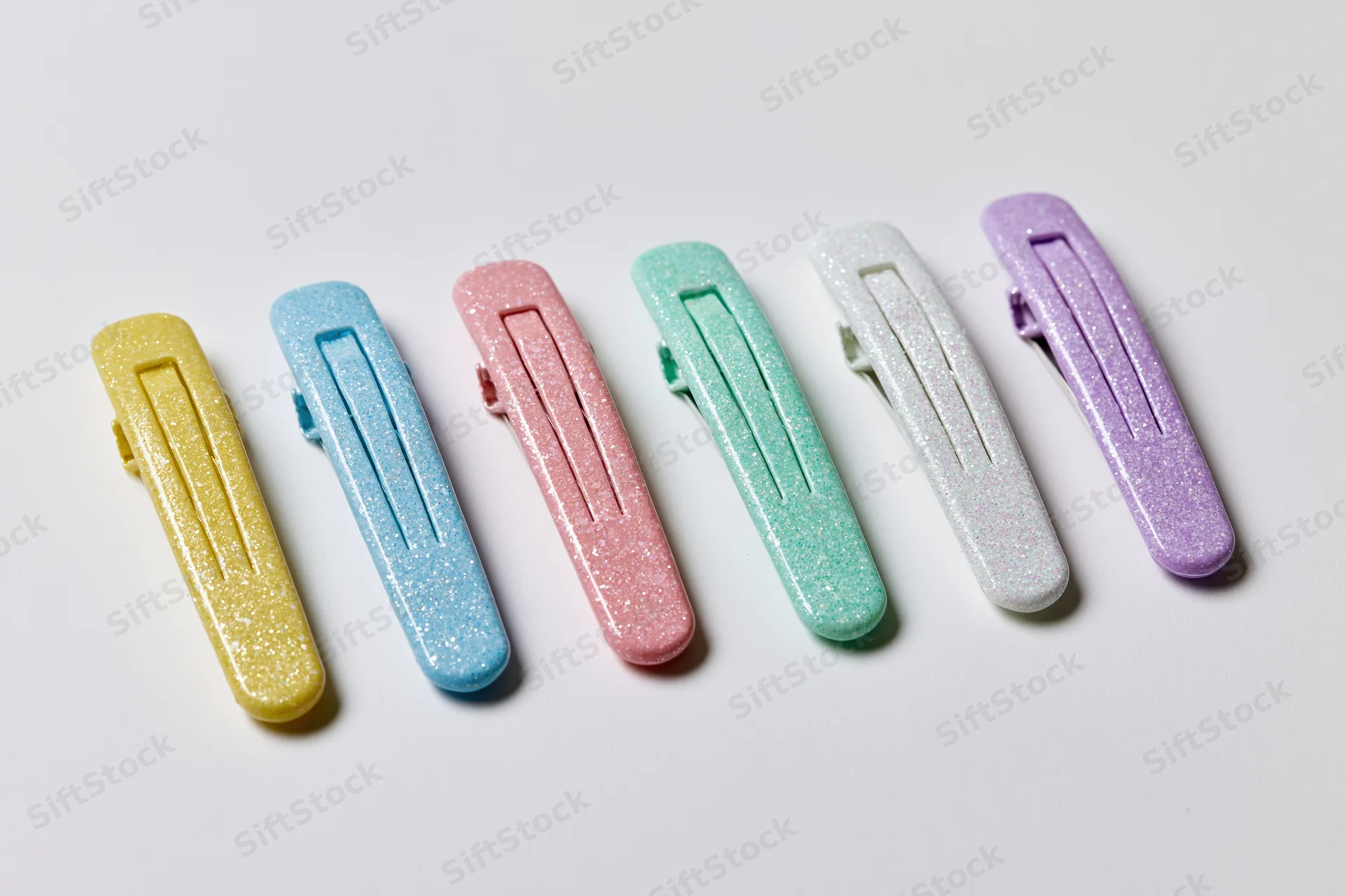 Six glitter snap hair clips arranged in a neat horizontal row on white background