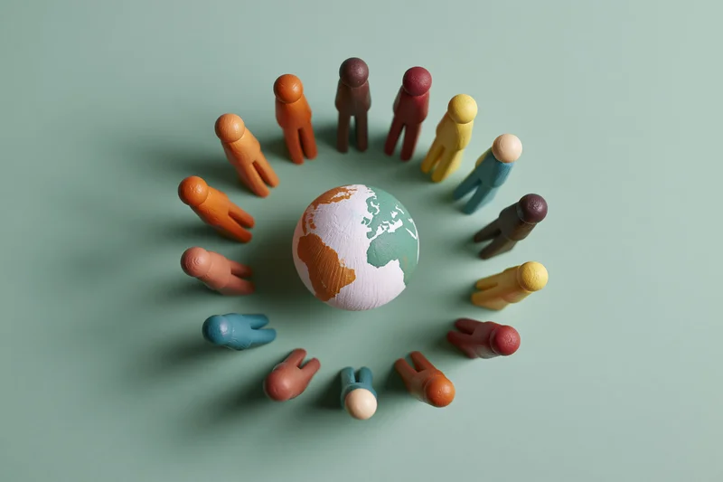 Painted miniature figurines arranged in a circle around a globe on a plain surface