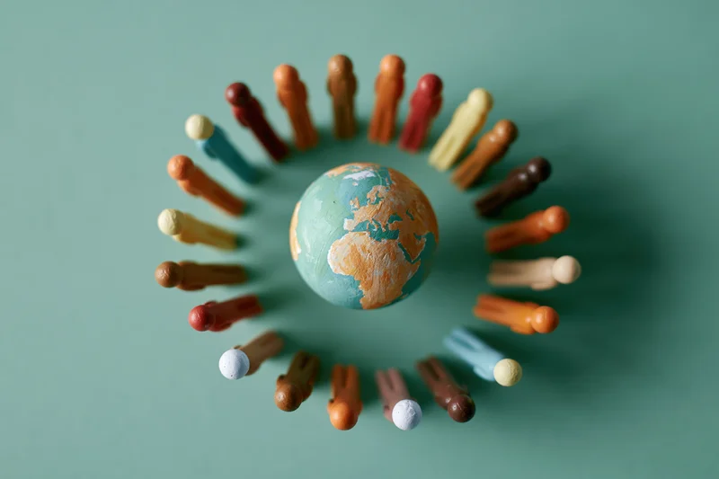 Miniature figurines arranged in a circle around a painted globe on a green surface