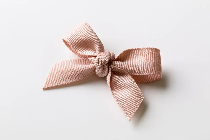 Pale pink grosgrain ribbon bow centered on white background