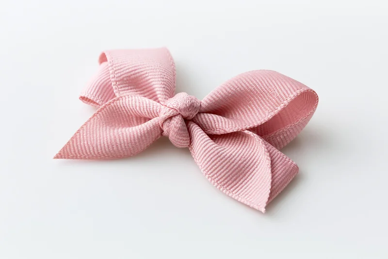 Pale pink grosgrain ribbon bow centered on white background