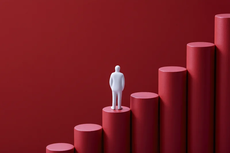 White figurine standing on ascending red columns against a red background