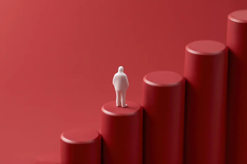 White figurine standing on rising red columns representing growth and progress