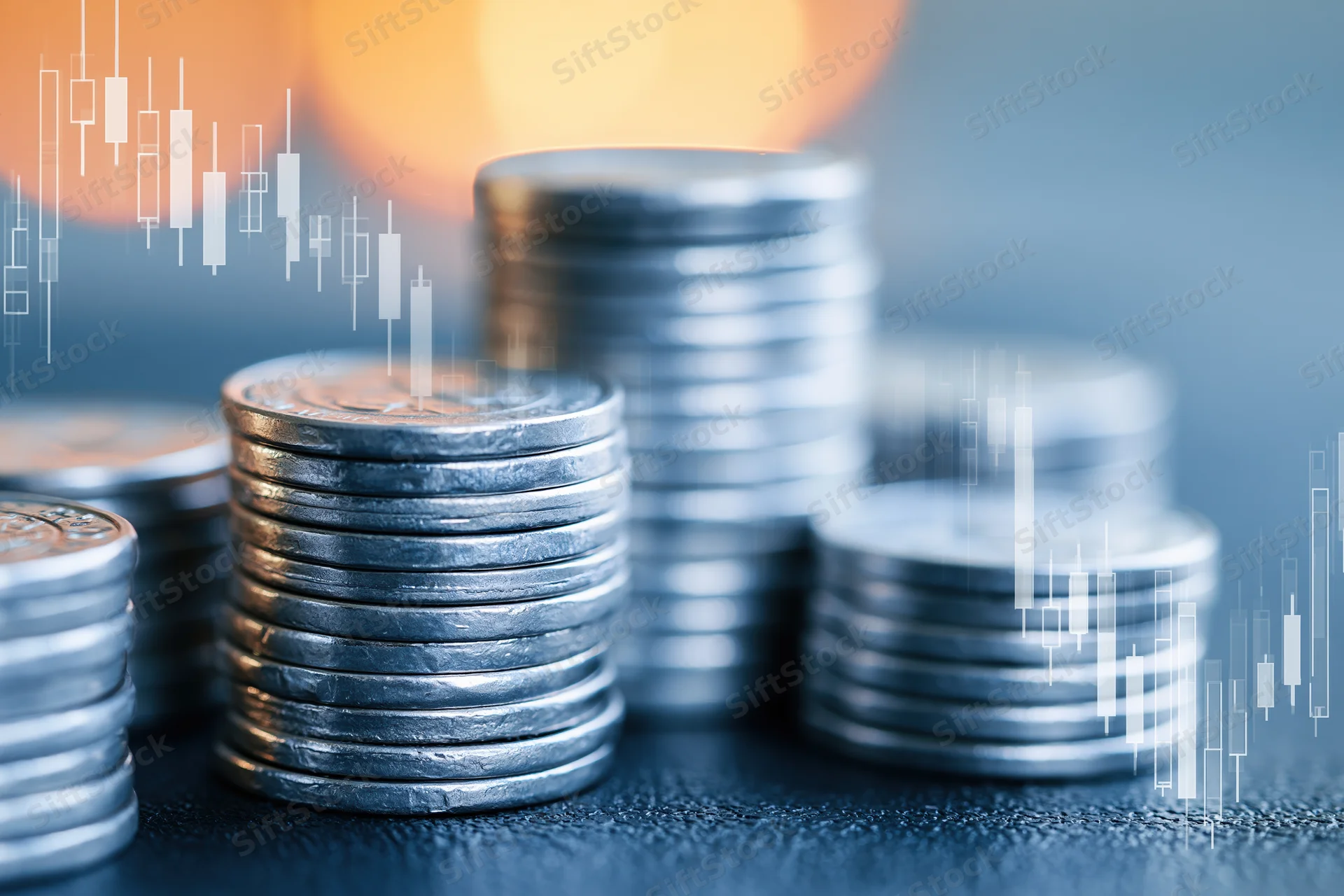 Stacks of silver coins on dark surface with candlestick chart overlay indicating market trends