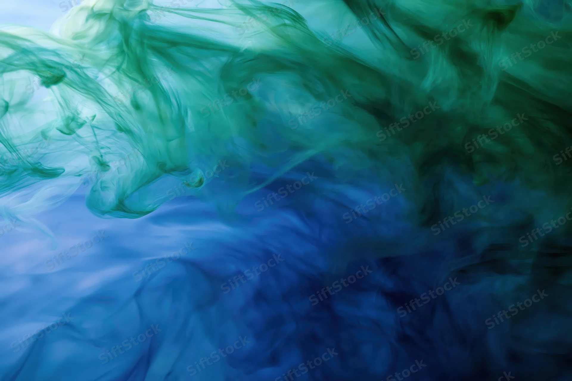 Swirling green and blue ink dispersing in water in a full-frame abstract composition