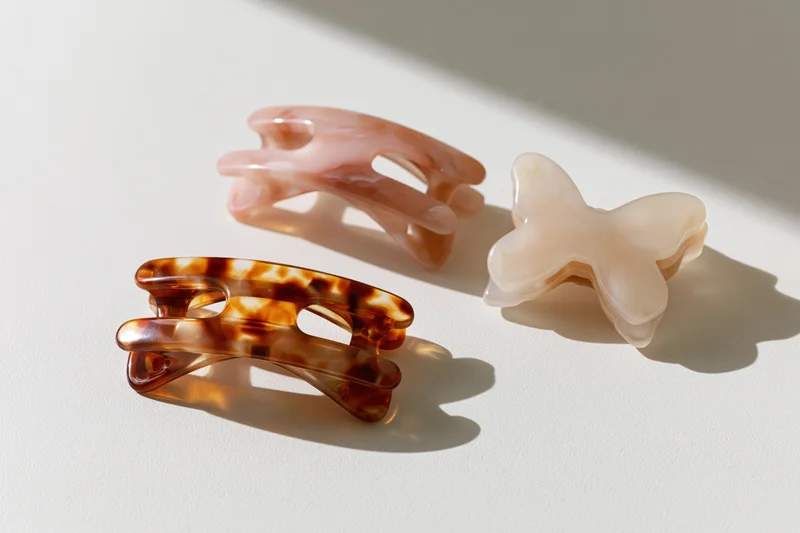 Three acetate hair claw clips arranged on a white surface with soft shadows